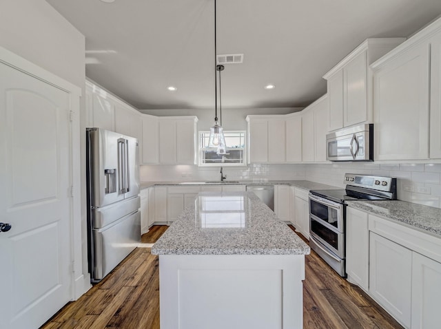 kitchen featuring visible vents, backsplash, a center island, and appliances with stainless steel finishes