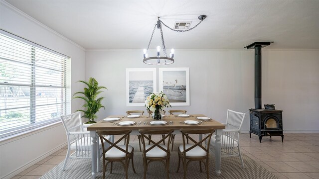 dining room featuring a wood stove, visible vents, baseboards, an inviting chandelier, and light tile patterned flooring
