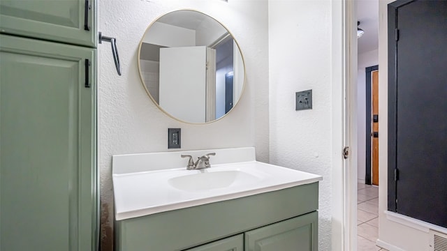 bathroom with tile patterned floors, a textured wall, and vanity