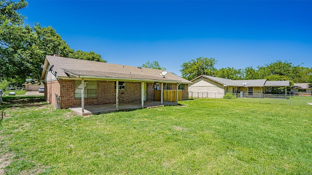 back of property with a lawn, fence, a patio, and brick siding
