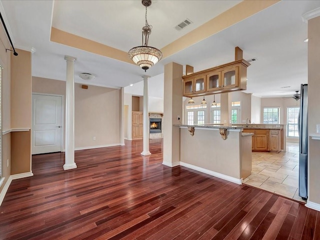 1904 Loblolly Ln, Lufkin, TX 75904 - unfurnished dining area featuring ornate columns, light wood finished floors, a sink, a lit fireplace, and ceiling fan