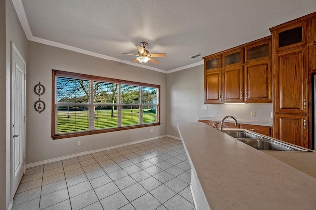 4489 E Fm 120, Denison, TX 75021 - kitchen with brown cabinetry, a ceiling fan, light tile patterned flooring, a sink, and baseboards