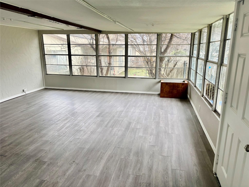 8805 N Normandale St, Fort Worth, TX 76116 - unfurnished sunroom with baseboards, wood finished floors, and a textured wall