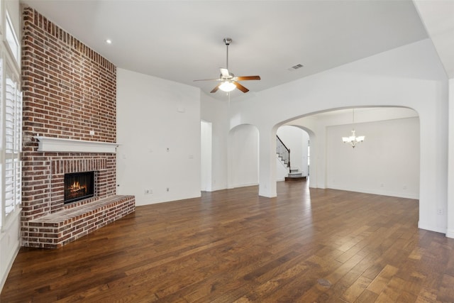 3612 Green Mountain Pl, Mckinney, TX 75070 - unfurnished living room featuring ceiling fan, a brick fireplace, arched walkways, wood finished floors, and a chandelier