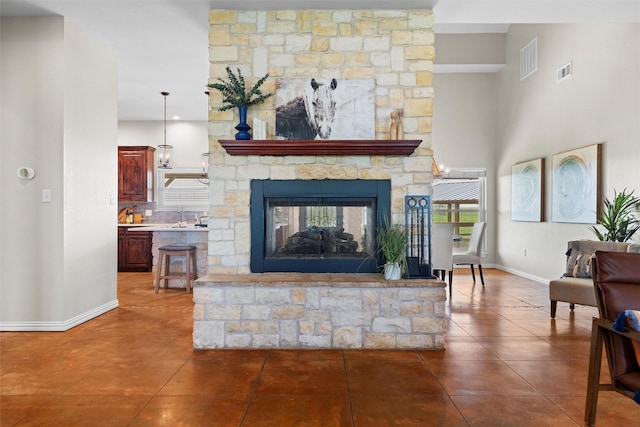 tiled living area featuring visible vents, baseboards, and a stone fireplace