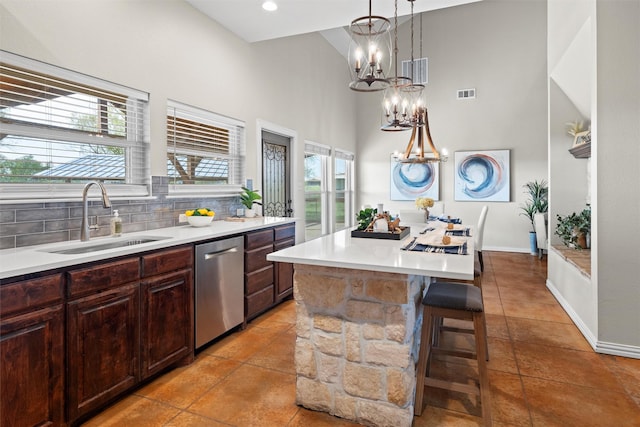 kitchen with a sink, visible vents, a towering ceiling, dishwasher, and a chandelier