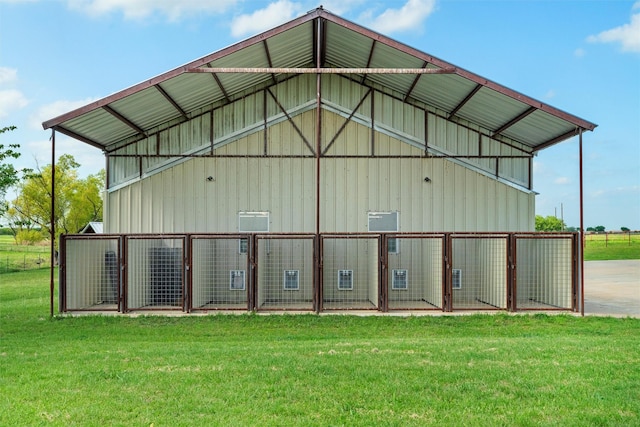 back of house with board and batten siding, an outbuilding, a lawn, and a pole building