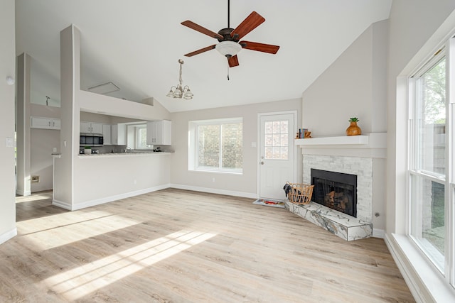 632 Albrook Dr, Allen, TX 75002 - unfurnished living room with a ceiling fan, light wood-style floors, a stone fireplace, baseboards, and high vaulted ceiling