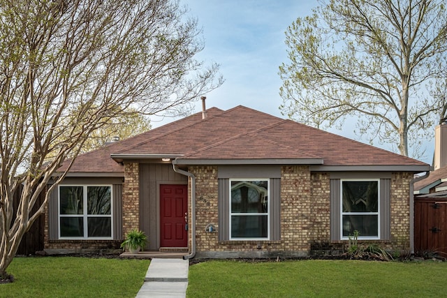 ranch-style home featuring a front lawn, brick siding, and a shingled roof