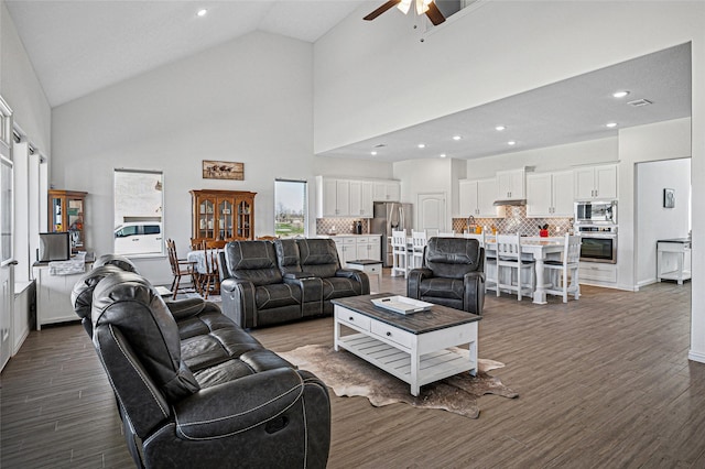 living area featuring recessed lighting, visible vents, a ceiling fan, dark wood-type flooring, and high vaulted ceiling