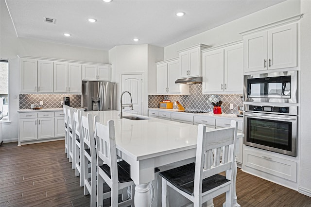 kitchen featuring white cabinetry, stainless steel appliances, decorative backsplash, and a sink