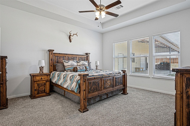 bedroom with ceiling fan, carpet flooring, baseboards, visible vents, and a raised ceiling