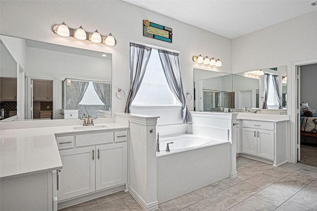 full bathroom featuring two vanities, walk in shower, a bath, and a sink