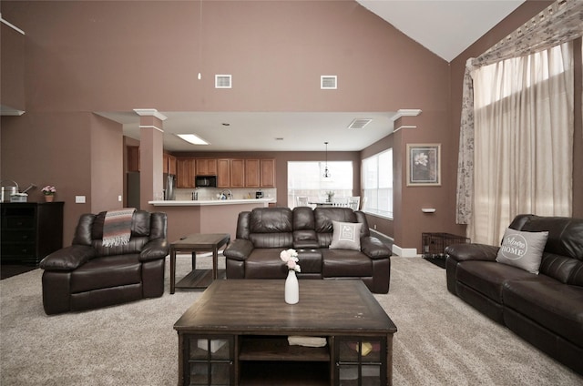 living area with high vaulted ceiling, visible vents, and light colored carpet