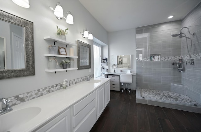 full bathroom with a tile shower, a sink, and double vanity