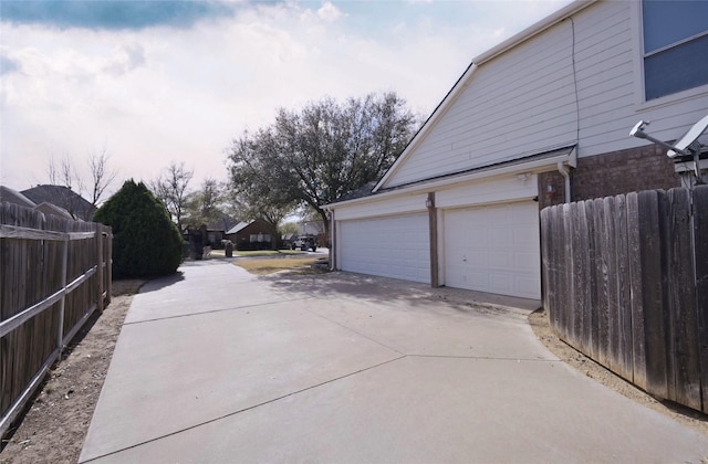 exterior space with fence, driveway, and a garage