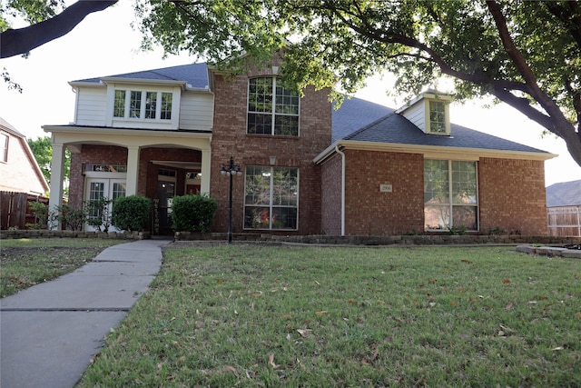traditional home featuring brick siding, french doors, and a front yard