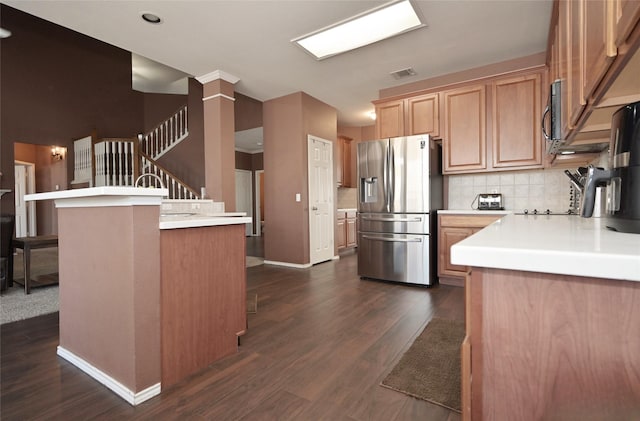 kitchen featuring dark wood-type flooring, light countertops, stainless steel refrigerator with ice dispenser, and baseboards