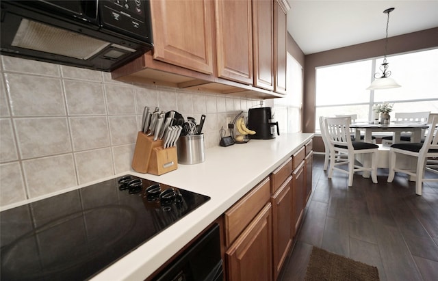 kitchen with extractor fan, backsplash, black electric stovetop, light countertops, and hanging light fixtures