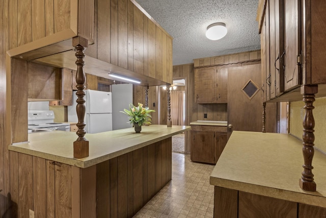 609 E Main, Omaha, TX 75571 - kitchen with light countertops, wood walls, a peninsula, a textured ceiling, and white appliances