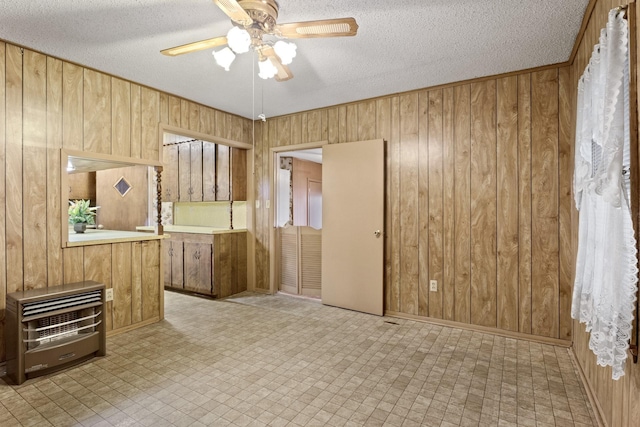 609 E Main, Omaha, TX 75571 - interior space with a textured ceiling, wooden walls, light floors, and a ceiling fan