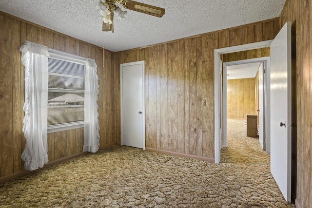 609 E Main, Omaha, TX 75571 - unfurnished bedroom featuring a textured ceiling, wood walls, a ceiling fan, and carpet