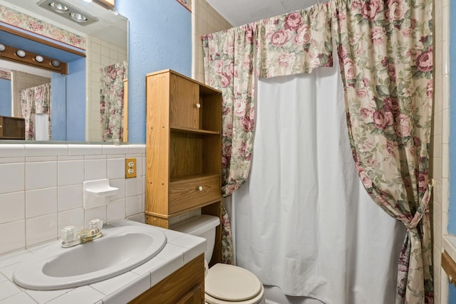 609 E Main, Omaha, TX 75571 - bathroom with tile walls, toilet, curtained shower, vanity, and a textured wall