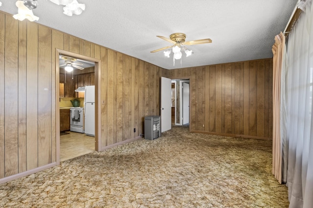 609 E Main, Omaha, TX 75571 - carpeted spare room with a textured ceiling, wooden walls, and a ceiling fan