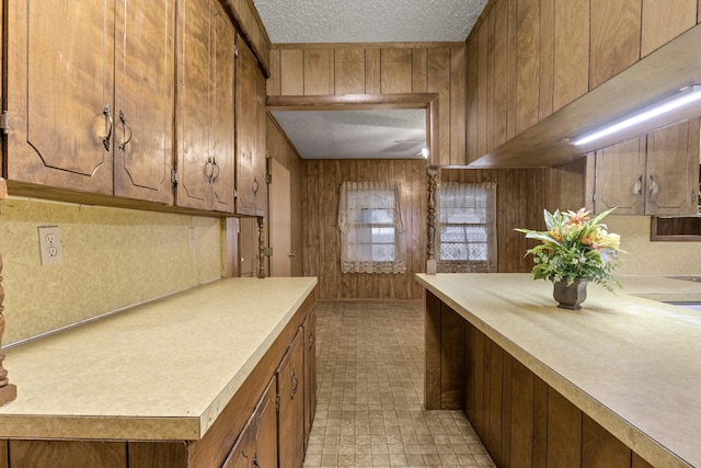 609 E Main, Omaha, TX 75571 - kitchen featuring wooden walls, light countertops, brown cabinetry, and a textured ceiling