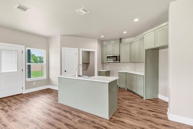 309 Pecan Ln, Tolar, TX 76476 - kitchen featuring stainless steel microwave, wood finished floors, baseboards, a center island with sink, and recessed lighting