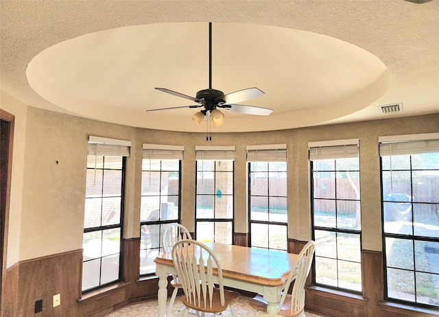 dining area with ceiling fan, a tray ceiling, and visible vents