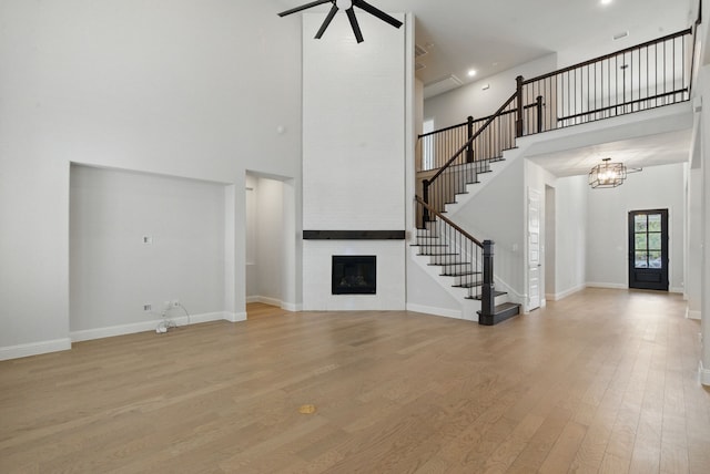 2205 Sandrellan St, Fort Worth, TX 76008 - unfurnished living room featuring stairs, a towering ceiling, a fireplace, wood finished floors, and a ceiling fan
