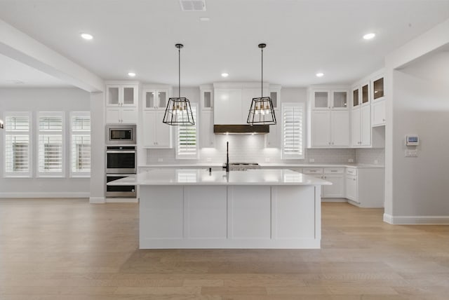 2205 Sandrellan St, Fort Worth, TX 76008 - kitchen with stainless steel appliances, tasteful backsplash, light countertops, light wood finished floors, and a kitchen island with sink