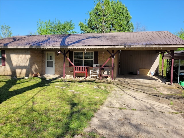 ranch-style home featuring a carport, driveway, metal roof, brick siding, and a front yard