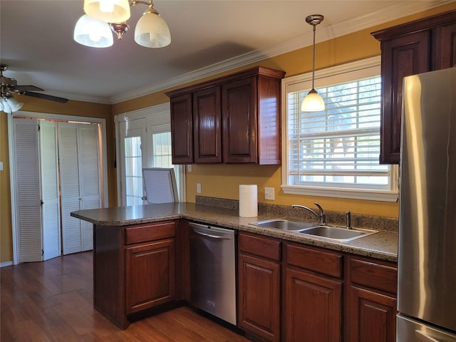 kitchen featuring dark countertops, a sink, stainless steel appliances, a peninsula, and dark wood-style floors
