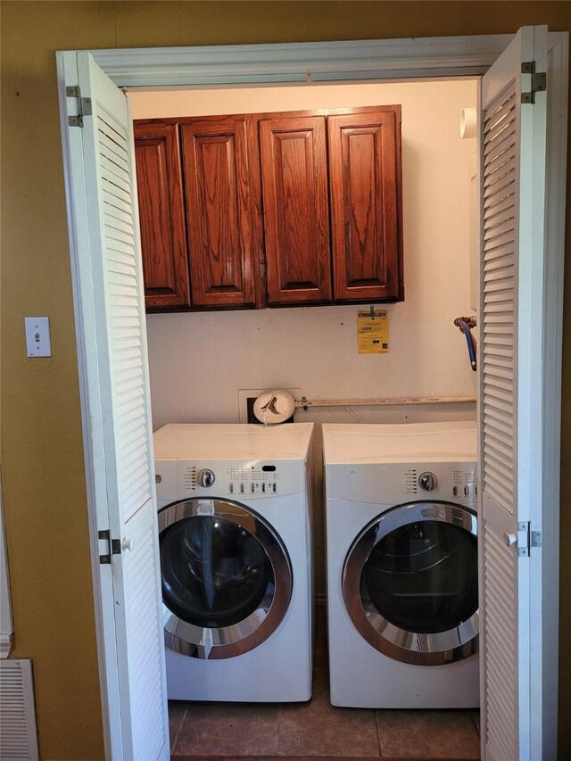 clothes washing area with cabinet space, washer and clothes dryer, and dark tile patterned flooring