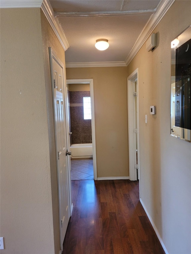 hallway featuring baseboards, ornamental molding, and wood finished floors