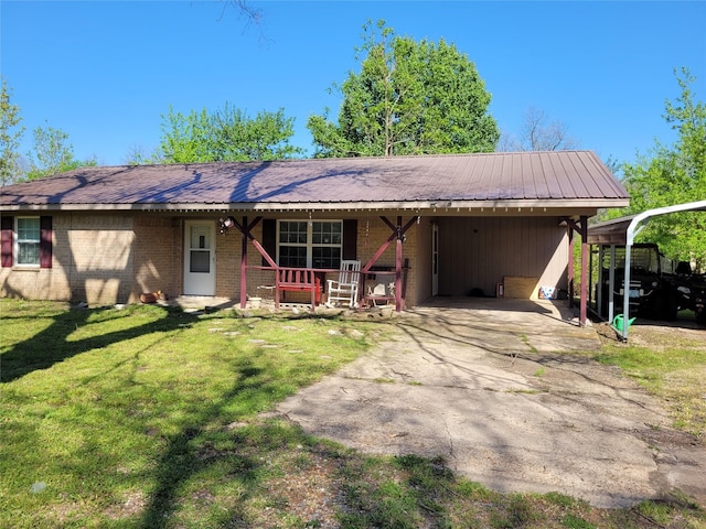 ranch-style house with metal roof, covered porch, brick siding, a front yard, and aphalt driveway