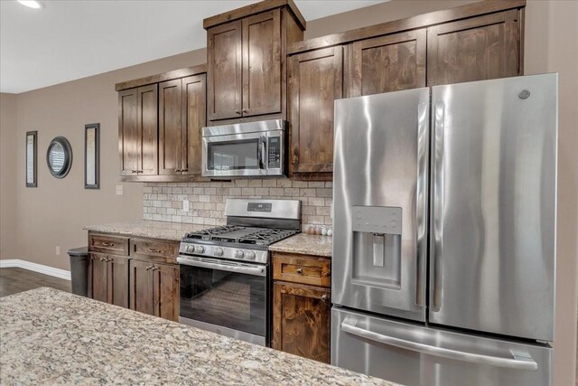 372 Private Road 123, Savoy, TX 75479 - kitchen featuring baseboards, backsplash, light stone countertops, dark brown cabinetry, and appliances with stainless steel finishes