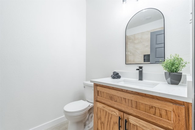 bathroom with toilet, vanity, and baseboards