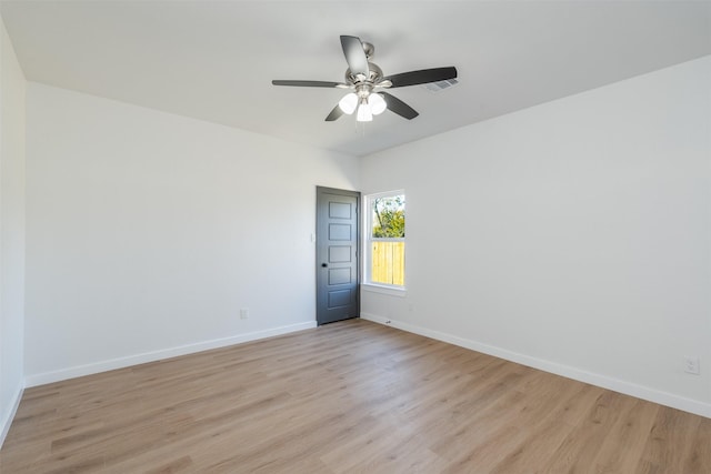 spare room with a ceiling fan, baseboards, visible vents, and light wood finished floors