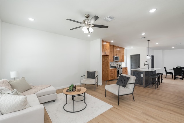 living room featuring ceiling fan, recessed lighting, visible vents, and light wood-style flooring