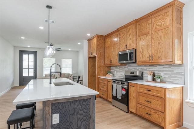 kitchen with backsplash, light countertops, visible vents, light wood-style flooring, and appliances with stainless steel finishes