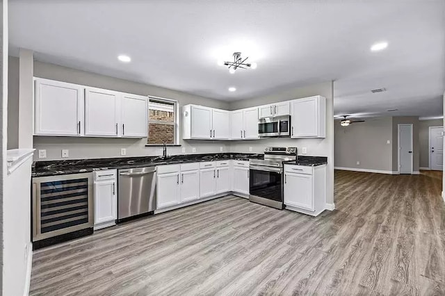 kitchen with wine cooler, a sink, dark countertops, visible vents, and appliances with stainless steel finishes