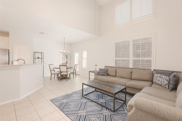 living area with baseboards, a high ceiling, a chandelier, and light tile patterned flooring