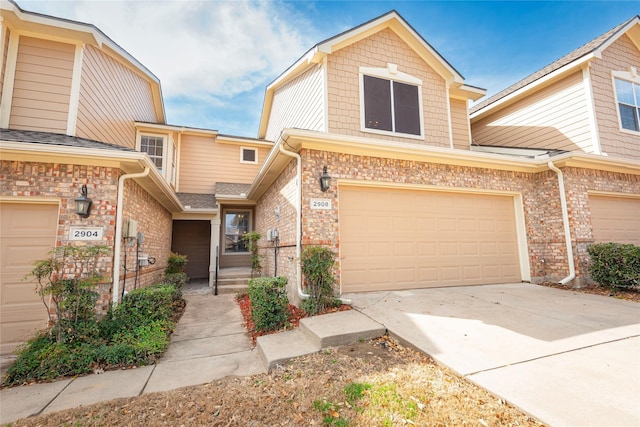 view of property with brick siding, driveway, and a garage