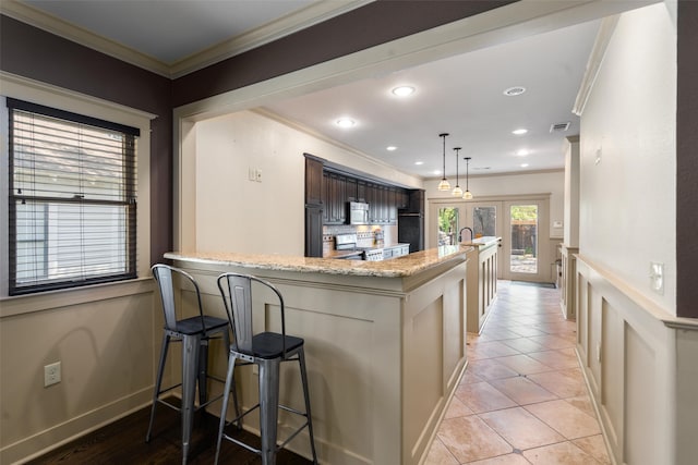 422 S Winnetka Ave, Dallas, TX 75208 - kitchen with ornamental molding, stainless steel appliances, light stone countertops, a breakfast bar area, and a sink