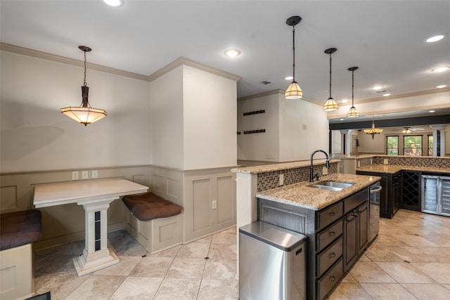 422 S Winnetka Ave, Dallas, TX 75208 - kitchen with a sink, crown molding, light stone counters, a wainscoted wall, and a center island with sink