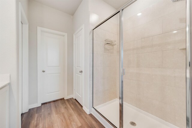 bathroom with wood finished floors, baseboards, and a shower stall