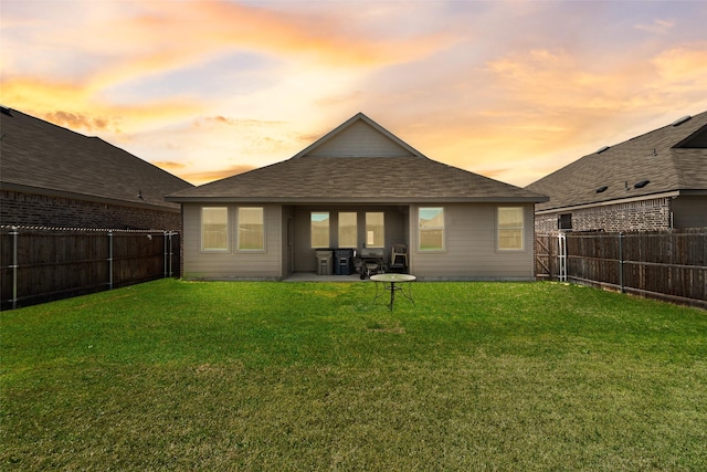 rear view of property with a fenced backyard, a patio, roof with shingles, and a lawn